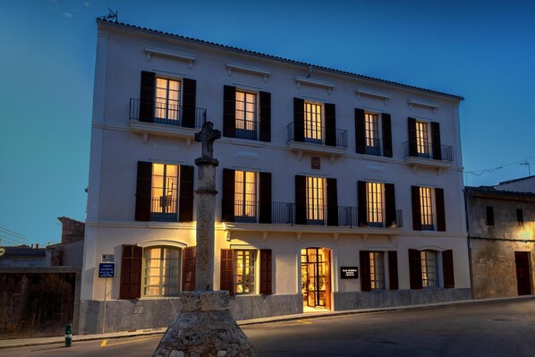A multi-story building with a central entrance, large windows with shutters, and a stone pillar in front. - Can Ribera By Zafiro (Muro)