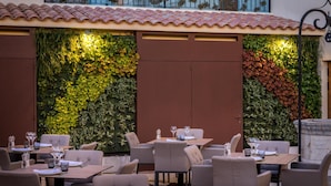 An outdoor dining area with tables and chairs, surrounded by vertical gardens with various plants. - Can Ribera By Zafiro (Muro)