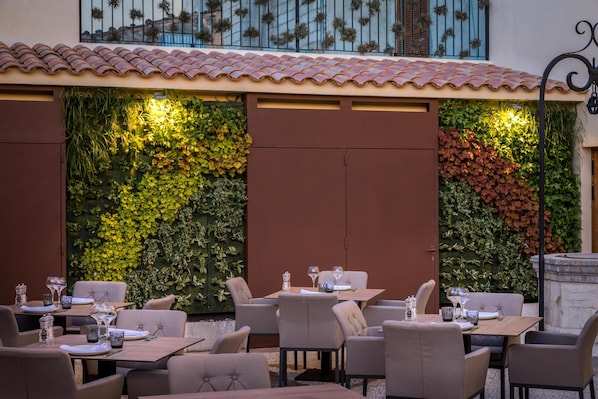 An outdoor dining area with tables and chairs, surrounded by vertical gardens with various plants. - Can Ribera By Zafiro (Muro)