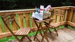 Une terrasse en bois avec deux chaises en bois et une petite table.