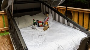 Un lit convertible avec un auvent, un petit panier de rangement et un drap blanc.
