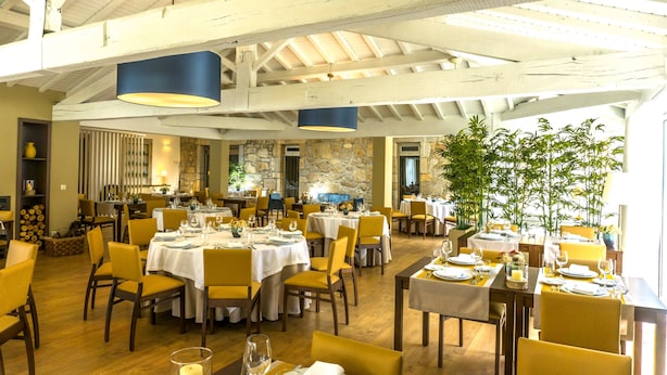 A spacious dining area with multiple tables and chairs, high ceilings with exposed beams, and large windows allowing natural light. - Casa Fundevila (Vila Verde)