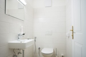 A bathroom with a white sink, toilet, and shower.