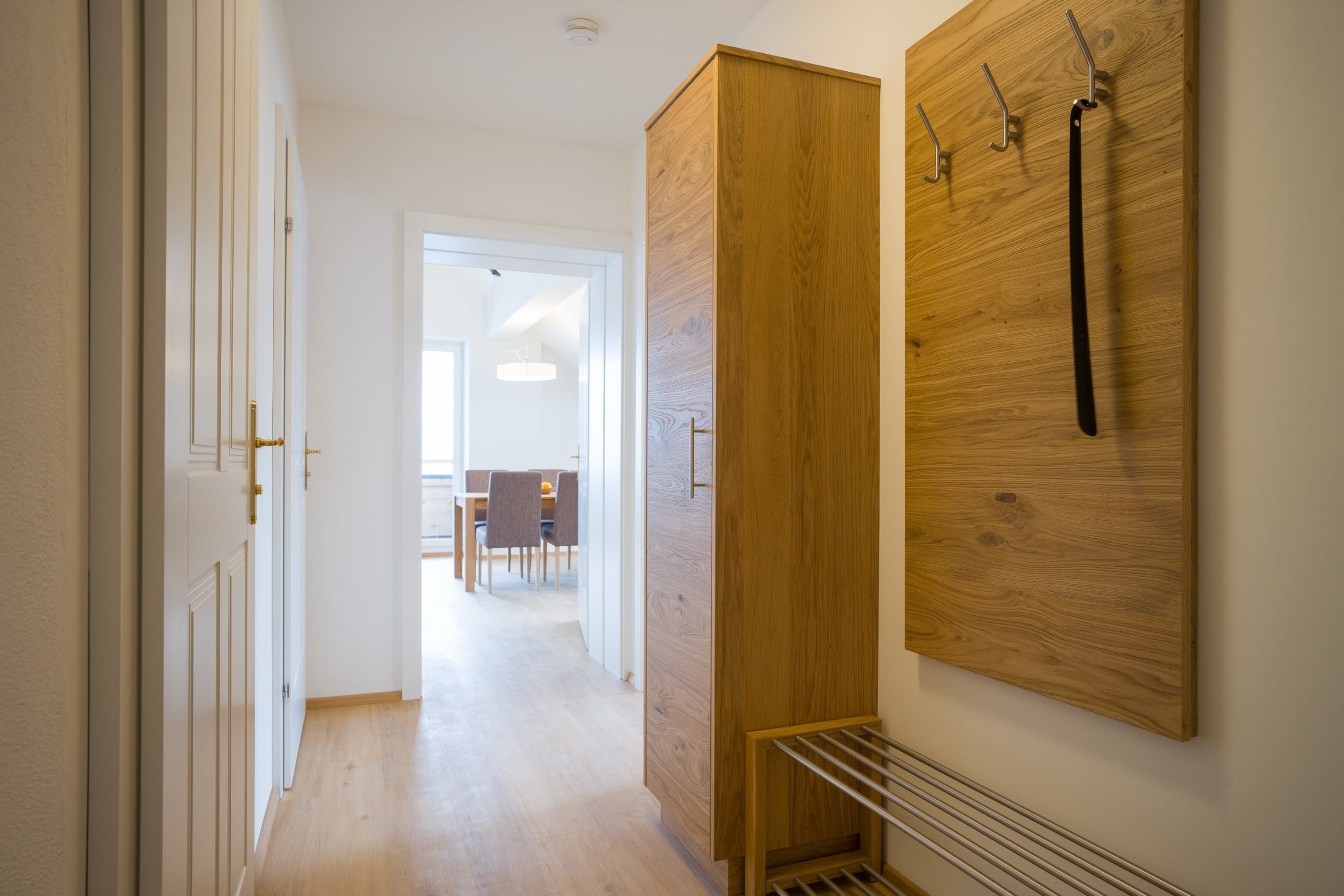 A hallway with a wooden wardrobe, a radiator, and a wall-mounted coat rack.