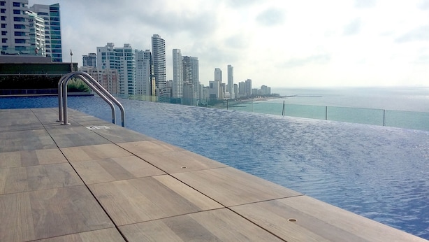 A poolside area with a view of a city skyline and the sea. - H2 LUXURY 3 Bedroom Apartment (Cartagena)