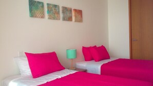 A hotel room with two beds, each with bright pink bedding and white pillows. There are three wall art pieces above the beds. - H2 LUXURY 3 Bedroom Apartment (Cartagena)