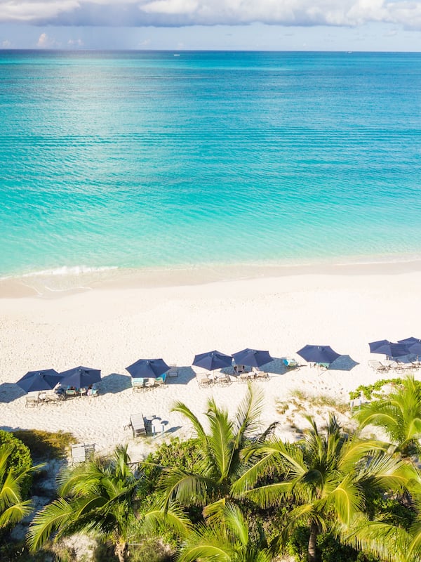 Na praia, areia branca, espreguiçadeiras, guarda-sóis