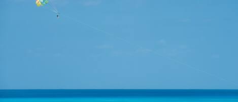 A clear blue sky with a colorful parachute above the ocean.