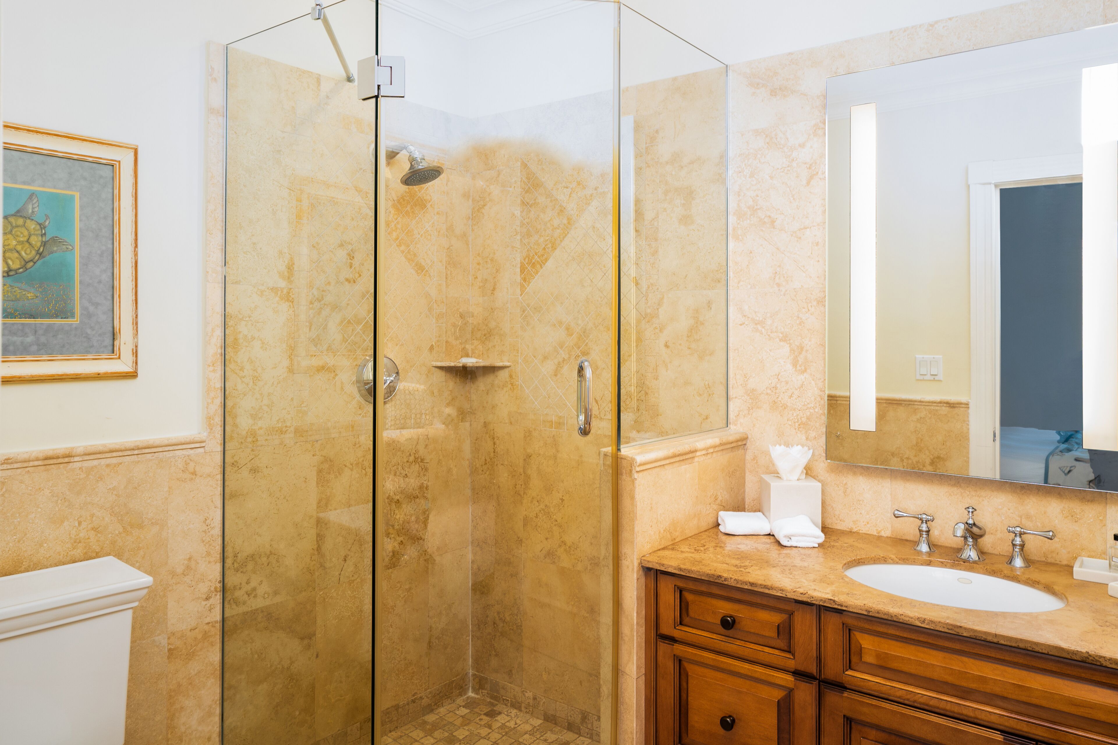 Ein Badezimmer mit einer Duschkabine, einem Waschbecken mit Spiegel und Holzschränken.
