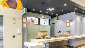Un comptoir d’accueil au design moderne, doté d’un long comptoir, de deux postes informatiques et d’un éclairage suspendu.