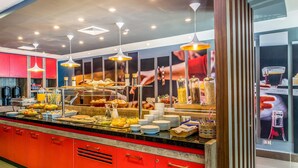 Un espace buffet avec un comptoir rouge, divers plats et un coin café.