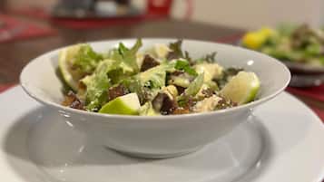 Un tazón de ensalada sobre un plato blanco.