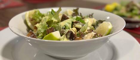 A bowl of salad on a white plate.
