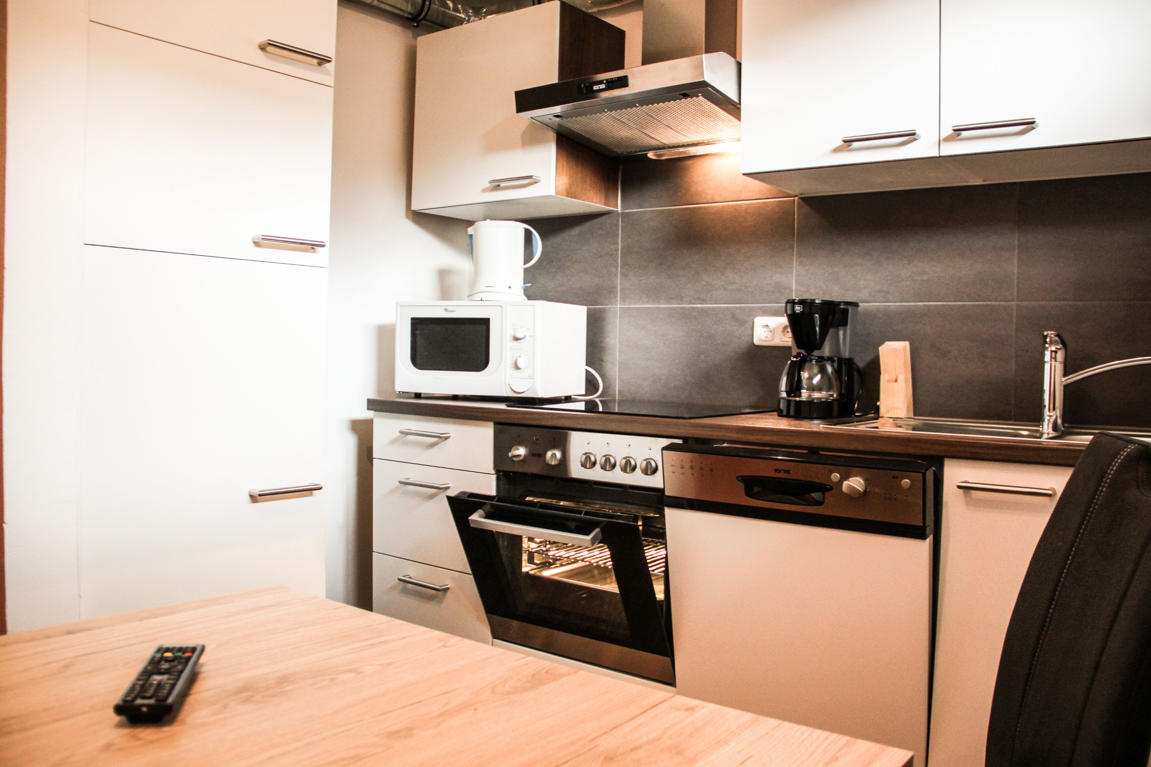 A compact kitchen with a microwave, coffee maker, oven, and dishwasher.