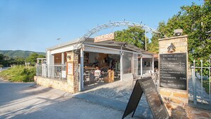 A cafe named ONEIRO with outdoor seating, a signboard listing prices for breakfast, full English, Bilt, omelettes, green scrambled eggs, coffee, and refreshments. - Dream House (Skiathos)