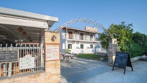 A restaurant with outdoor seating, a signboard, and a stone wall. - Dream House (Skiathos)