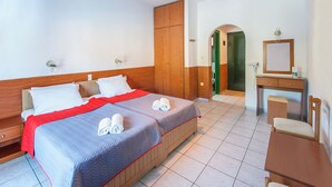 A hotel room with two beds, a wooden wardrobe, a small desk with a mirror, and a bathroom visible through an archway. - Dream House (Skiathos)