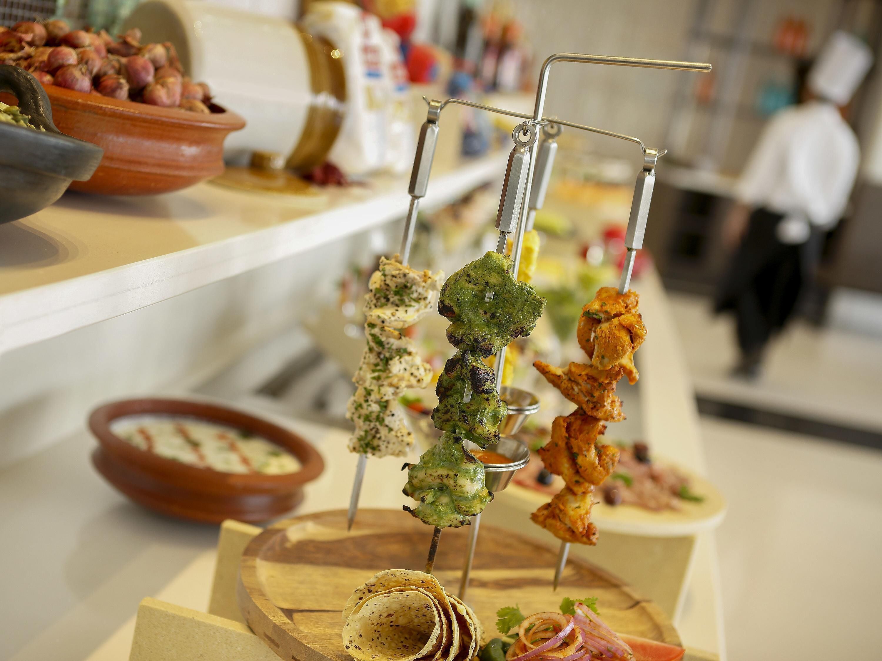 Un buffet allestito con diversi piatti, tra cui spiedini e una ciotola di insalata.