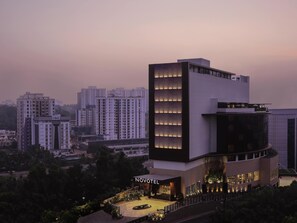 A modern hotel with a prominent vertical design, a courtyard, and a view of surrounding high-rise buildings.