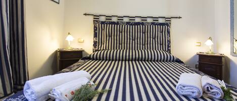 A neatly made bed with striped bedding, two bedside lamps, and a framed picture on the wall.
