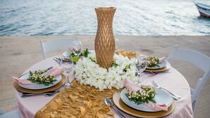 A round table with a pink tablecloth, gold accents, white flowers, and a tall vase. - Serene by the Sea (Savaneta)
