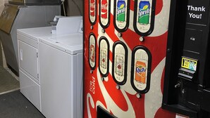 Ein Getränkeautomat mit verschiedenen Auswahlmöglichkeiten, darunter Coca-Cola, Sprite und Fanta.