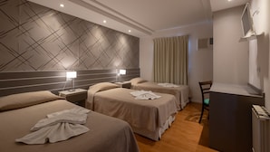 A hotel room with three beds, a desk, and a mirror. - Hotel La Posta (Oncativo)