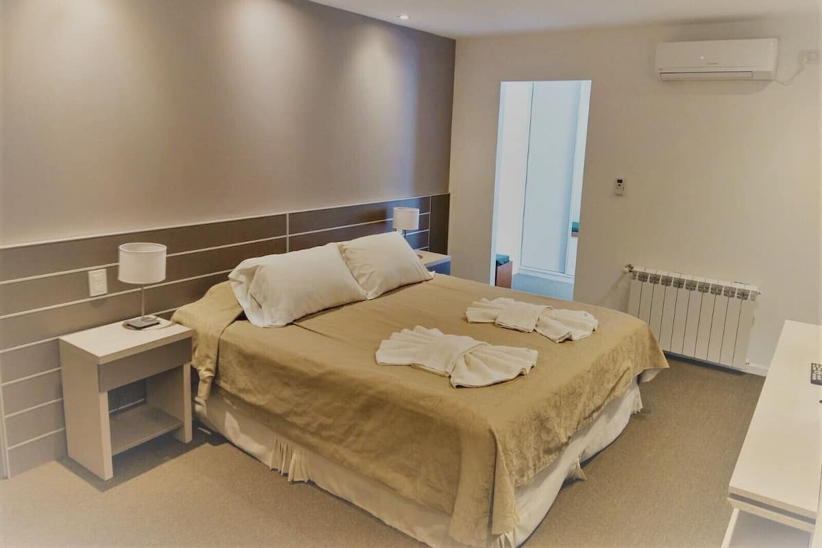 Una camera d'albergo moderna con un letto grande, comodini, una scrivania e una finestra con vista.
