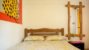 A bed with a floral bedspread, a wooden headboard, and a nightstand with a lamp.