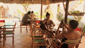 A restaurant with outdoor seating, thatched roofs, and tiled flooring.