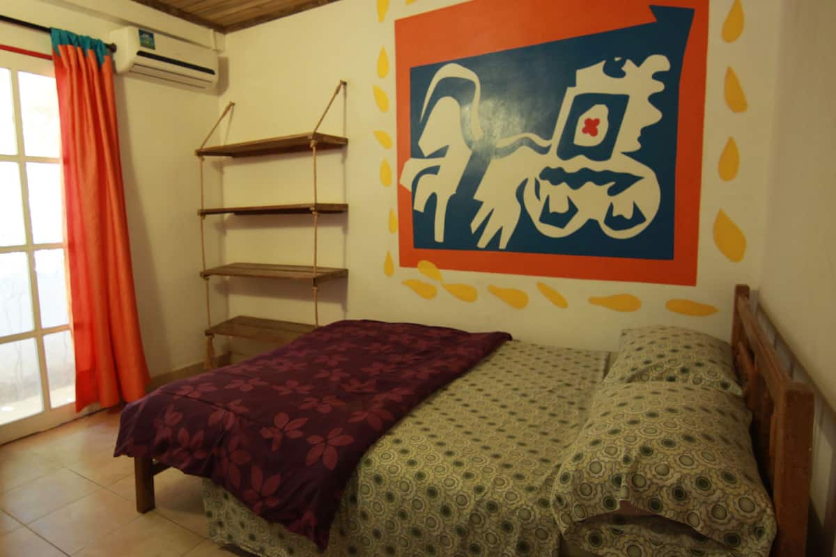 Une chambre à coucher avec un lit, un bureau et une fenêtre avec des rideaux.