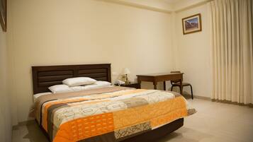 A hotel room with a bed, a desk, a chair, and a nightstand.