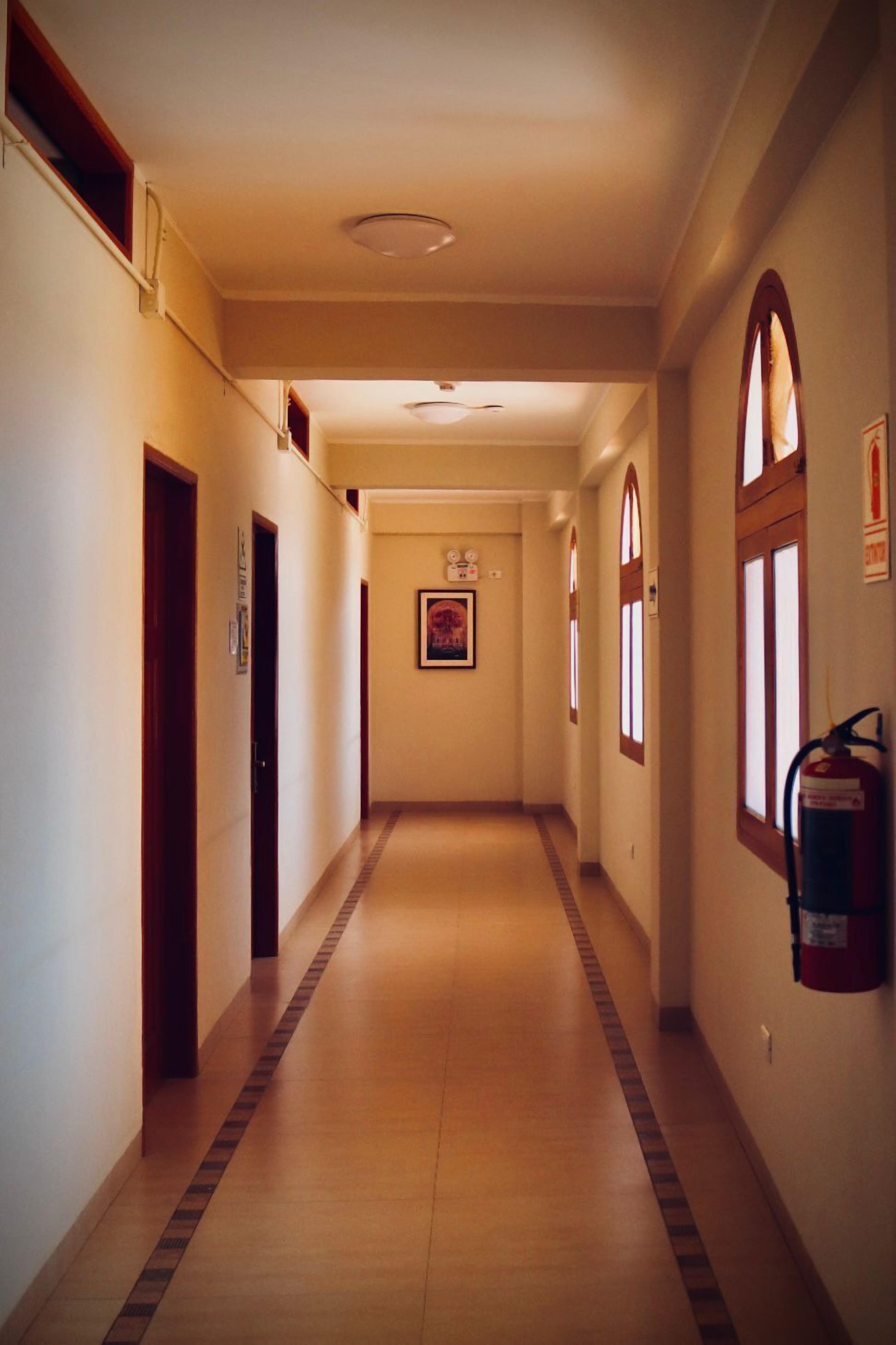 A long, narrow hallway with wooden floors and arched windows on one side.