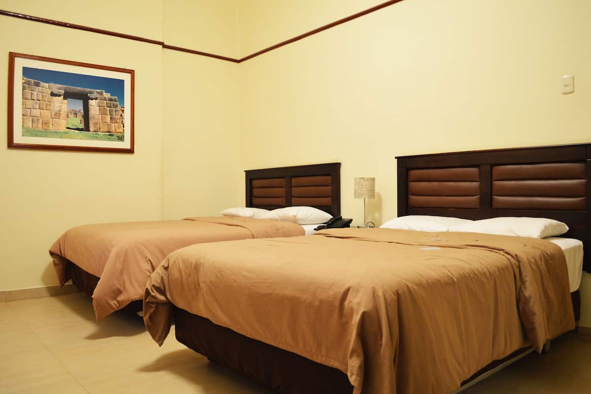 Une chambre d’hôtel avec deux lits, des murs de couleur beige et un tableau représentant une structure ancienne.
