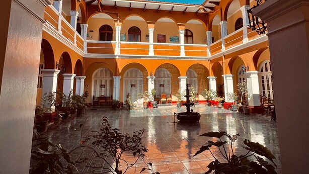 An open courtyard with a fountain, potted plants, and a tiled floor.