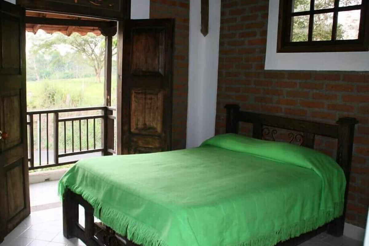 A bedroom with a wooden bed, a balcony door, and a brick wall.