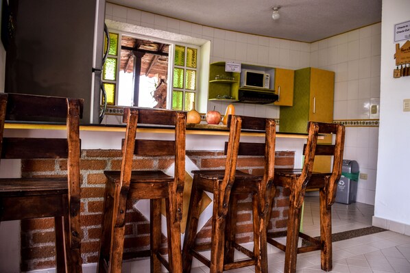 A kitchen with wooden chairs, a brick wall, and a window with a view.