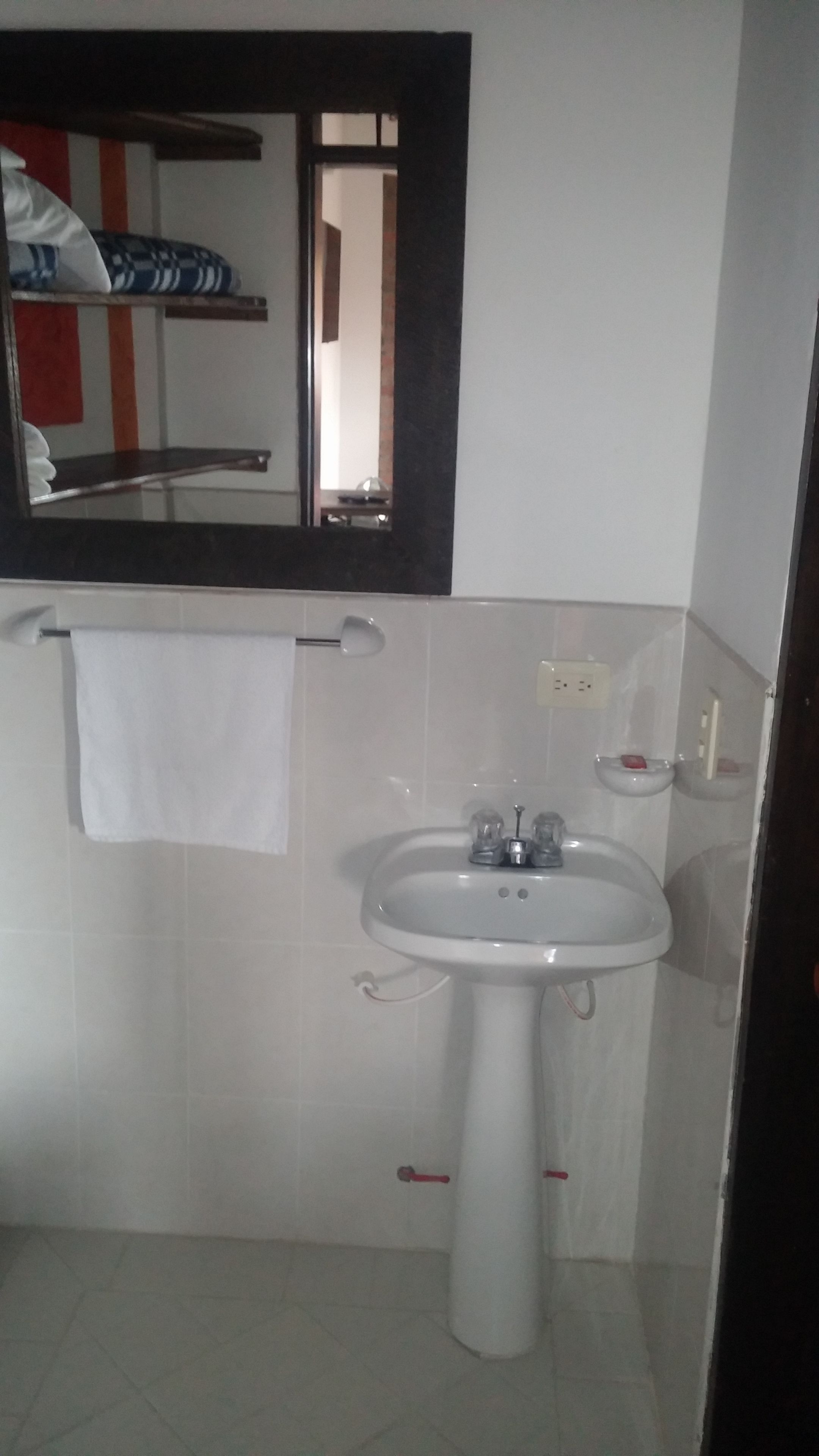 A bathroom with a white sink, a mirror, and a towel hanging on the wall.