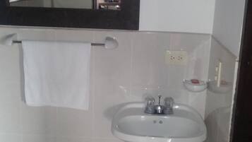 Ein Badezimmer mit einem weißen Waschbecken, einem Spiegel und einem Handtuch, das an der Wand hängt.