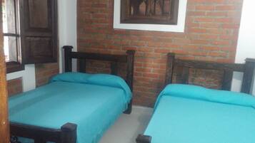A room with two beds, a brick wall, and a framed picture on the wall.