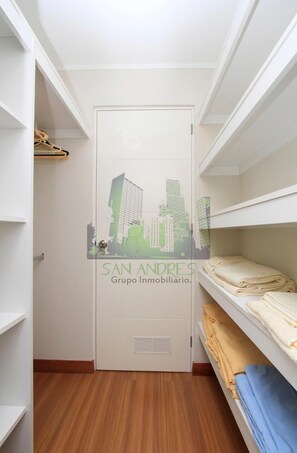 A narrow hallway with wooden flooring, white walls, and a door with a cityscape decal.