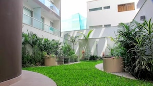 Um pátio moderno com gramado, plantas em vasos e um caminho curvo.
