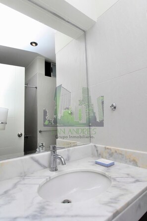 A modern bathroom with a large mirror, a sink, and a shower.