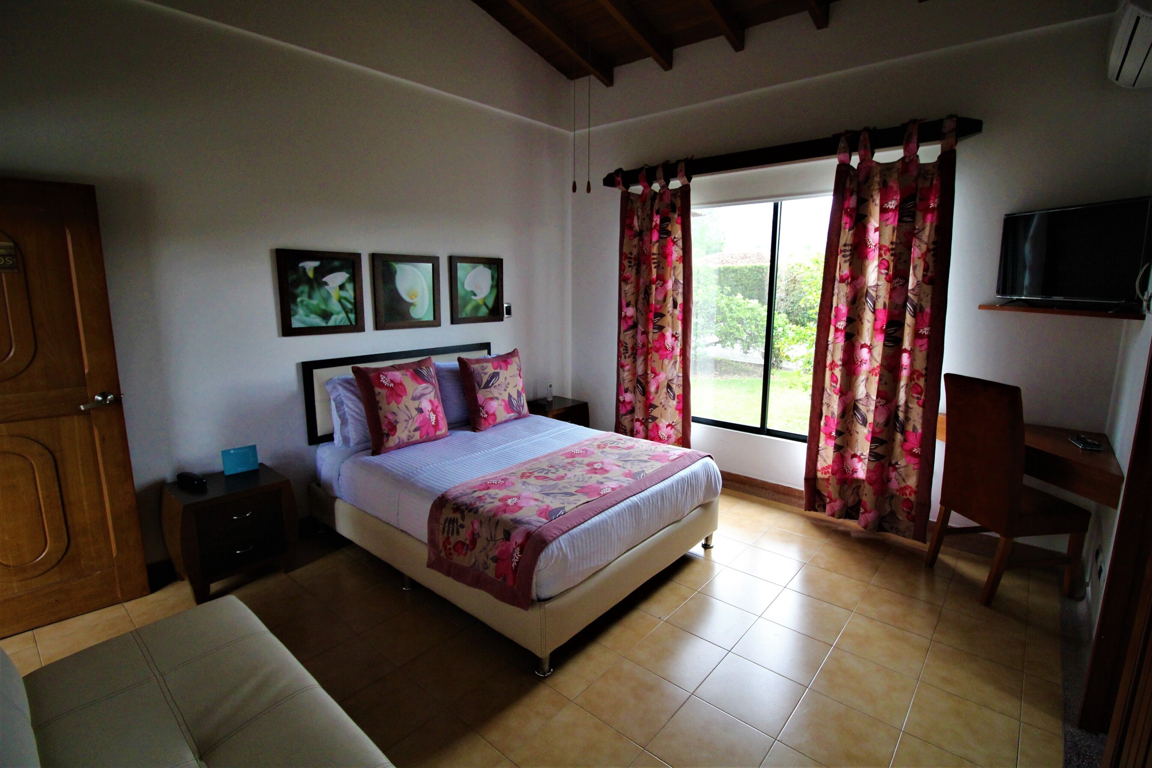 A bedroom with a bed, a desk, and a TV.
