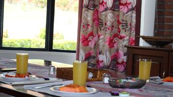Una mesa de desayuno servida con platos, un bol y dos vasos de zumo de naranja.