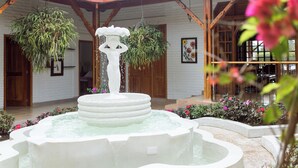 A fountain with multiple tiers and water spouts, surrounded by a garden with various plants and flowers. - Amazilia Hotel (Pereira)