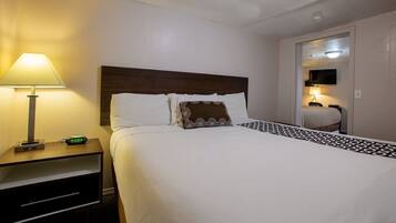 A hotel room with a bed, a nightstand with a lamp, and a television in the corner.