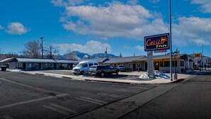 Celilo Inn mit einem Schild, einem weißen Van vor der Fassade und einem Gebäude im Hintergrund mit Bergblick.