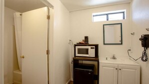 A compact kitchen with a microwave, refrigerator, and a small window above the sink. - Celilo Inn (Williams)