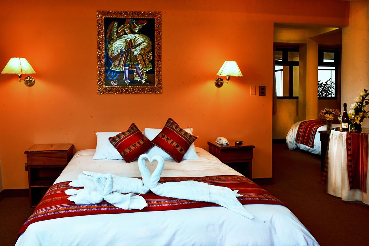 A hotel room with a bed, two nightstands, a painting, and two lamps.
